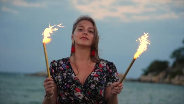 Junge glücklich lächelnde Frau, die mit Wunderkerzen im Sonnenuntergang in Zeitlupe eintanzt, mit Feuerwerk bei Sonnenuntergang am Strand. — Stockvideo