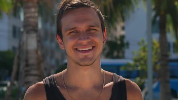 Close Up Retrato Jovem Caucasiano de Bonito Homem Morena uma Barba Olhando para a Câmera Sorrisos, no Céu Azul Fundo . — Vídeo de Stock