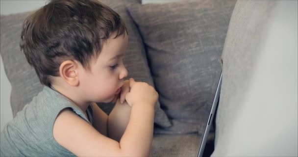 Χαριτωμένο παιδί διασκέδαση με το tablet. Μικρό αγόρι ξοδεύει ελεύθερο χρόνο παίζοντας κινητό παιχνίδι στο και συντρίβει την φωτεινή οθόνη με το χέρι της. Ιδέα: καλή παιδική διατροφή, τεχνολογία, παιχνίδια — Αρχείο Βίντεο