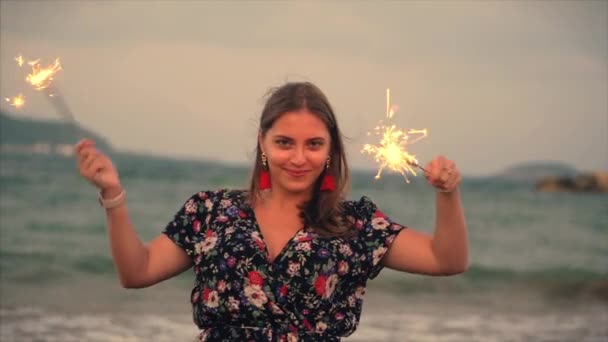 Young Happy Smiling Woman, Dancing in With Sparkler at Sunset in Slow Motion, with Fireworks at Sunset on Beach. — Stock Video