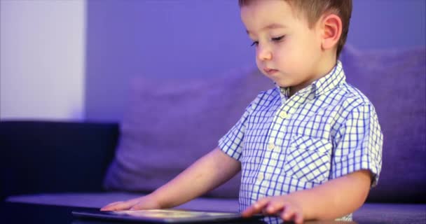 Lindo niño entreteniendo con la tableta. Little Boy pasar el tiempo libre jugando juego móvil en el y aplasta la pantalla brillante con su mano. Concepto de: Comida Infantil Feliz, Tecnología, Juegos de Juego Infantil — Vídeo de stock