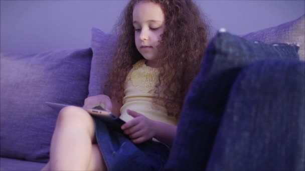 Portrait photo de nuit d'un enfant mignon caucasien, petite fille gros plan d'un visage d'enfant regardant une tablette PC avec un reflet et des photos dans ses yeux . — Video