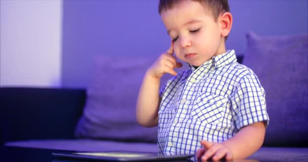 Criança bonito entretendo com Tablet. Little Boy gasta tempo de lazer jogando jogo móvel no e esmaga a tela brilhante com sua mão. Conceito de: Happy Childfood, Tecnologia, Jogos infantis — Vídeo de Stock