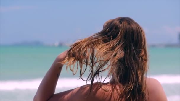 Close-up portret van de Europese mooie schattige brunette jonge vrouw of vrolijk meisje op zoek naar de zee, het runnen van zijn hand over het haar waait in de wind op een tropisch strand, Slow Motion. — Stockvideo