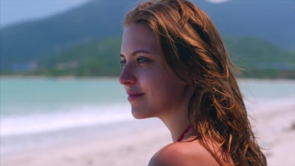 Zavřít portrét Evropské krásné rozkošné brunety mladá žena nebo veselá dívka usmívající se pohled na kameru, tekoucí ruku přes vlasy foukající ve větru na tropické pláži, pomalý pohyb. — Stock video