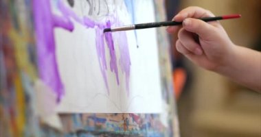 Sanatçının genç elleri, küçük kadın sanatçı fırça ile bir tuval boyar, bir masa oturan ve tuval üzerine çizin. Çizim süreci: sanatçılar sanat stüdyosu el bebek kız Canvas. Shot üzerinde çizim