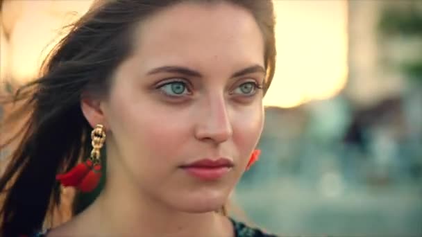 Zavřít portrét roztomilá hnědá žena se zelenými očky s tekoucí vlasy v letních šatech s obrázkem červených a bílých květů, které se v létě dívají na výhled. Měkké zaměření — Stock video
