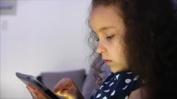 Schattig kind onderhoudend met Tablet. Little Girl besteden vrije tijd spelen mobiele spel in de en verplettert het heldere scherm met haar hand. Concept: Happy Childfood, technologie, kinderspelen — Stockvideo