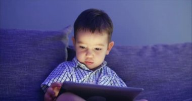 Tablet Ile eğlenceli sevimli çocuk. Küçük çocuk harcama boş zaman oynamak mobil oyun ve El Ile parlak ekran Hahes. Konsept: mutlu Childfood, teknoloji, Childen oyun oyunları