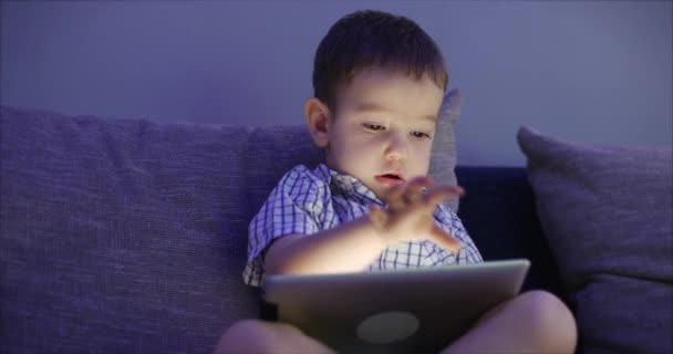 Criança bonito entretendo com Tablet. Little Boy gasta tempo de lazer jogando jogo móvel no e esmaga a tela brilhante com sua mão. Conceito de: Happy Childfood, Tecnologia, Jogos infantis — Vídeo de Stock