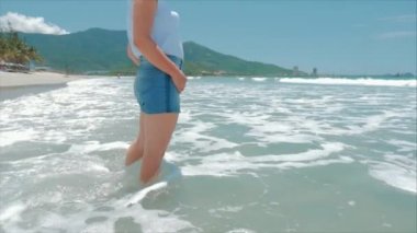 Bir tropikal Plaj yakın çekim kadın bacaklar Avrupa güzel esmer, plaj boyunca yürüyüş, yavaş hareket.