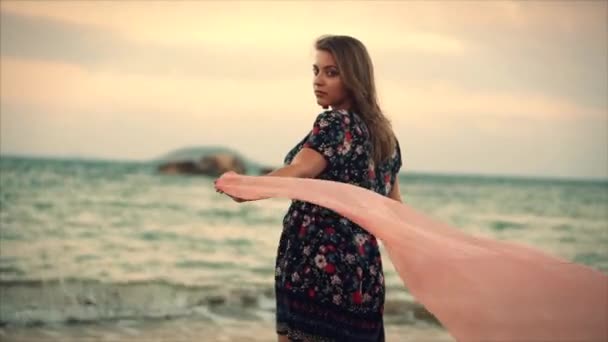 Fermer Portrait Une merveilleuse femme aux cheveux bruns aux yeux verts avec des cheveux fluides dans une robe d'été avec une image de fleurs rouges et blanches contre l'arbre vert au coucher du soleil. Focus doux — Video