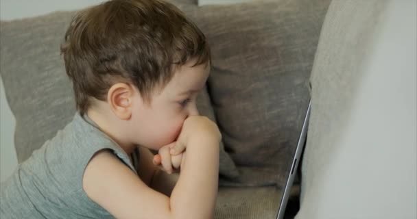 Χαριτωμένο παιδί διασκέδαση με το tablet. Μικρό αγόρι ξοδεύει ελεύθερο χρόνο παίζοντας κινητό παιχνίδι στο και συντρίβει την φωτεινή οθόνη με το χέρι της. Ιδέα: καλή παιδική διατροφή, τεχνολογία, παιχνίδια — Αρχείο Βίντεο