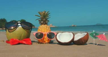 Bir tropikal Plaj yakın çekim meyve güneş gözlüğü tropikal sahil boyunca sıcak yaz güneşi altında, ananas ve Hindistan cevizi okyanus arka plan üzerinde kulaklıklar. Tropikal yaz partisi kavramı.