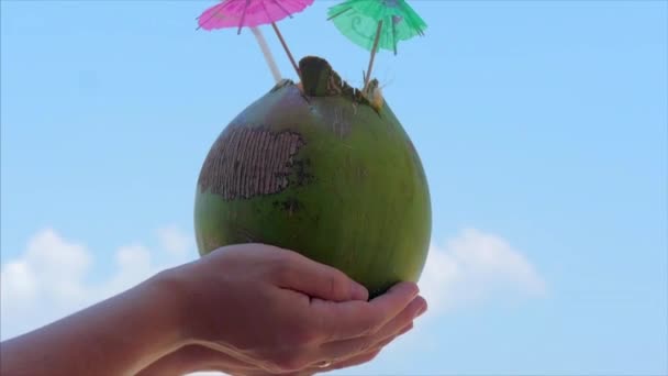 Unga händer Kvinnor som håller kokos i bakgrunden Vackra moln på en tropisk strand. Begreppet sommarsemester, resor. — Stockvideo