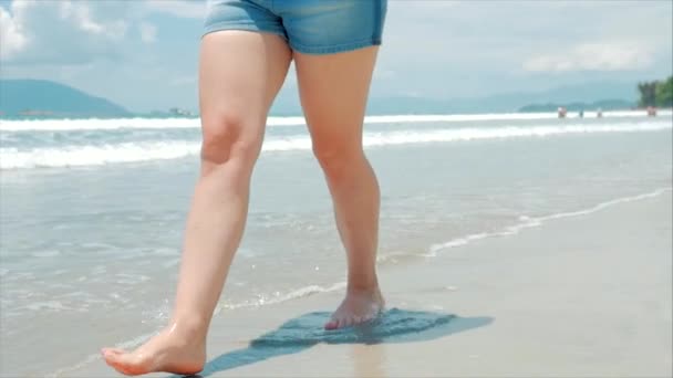 På en tropisk strand närbild av Womens Legs Europeiska vackra brunett, Walking längs stranden, slow motion. — Stockvideo