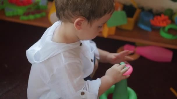 Niedliches kleines Kind, das im Spielzimmer mit Spielzeug spielt. Konzept glückliche Kindheit. — Stockvideo