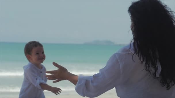 Gelukkige moeder knuffelen haar kind aan de kust. Schattig kind kusjes zijn moeder en zachtjes knuffels. Concept moeder met een kind buitenshuis, gelukkige familie, gelukkige kindertijd, kleine baby. — Stockvideo