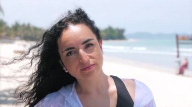 Bir Tropik Plajda Avrupa Güzel Sevimli Esmer Genç Kadın veya Neşeli Kız Kamera Bakıyor Yakın Çekim Portresi, Rüzgar Rüzgar Üfleme , Yavaş Hareket.