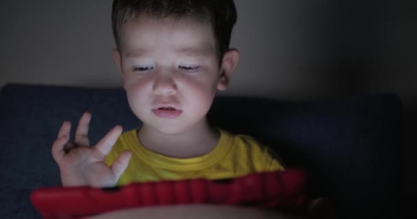 Anak manis Menghibur dengan Tablet. Little Boy Spending Leisure Time Playing Mobile Game in the and Crushes the Bright Screen With Her Hand (dalam bahasa Inggris). Konsep: Happy Childfood, Technology, Childen Play Games — Stok Video