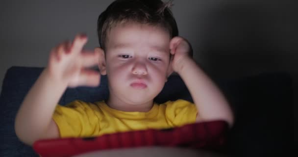 Lindo niño entreteniendo con la tableta. Little Boy pasar el tiempo libre jugando juego móvil en el y aplasta la pantalla brillante con su mano. Concepto de: Comida Infantil Feliz, Tecnología, Juegos de Juego Infantil — Vídeo de stock