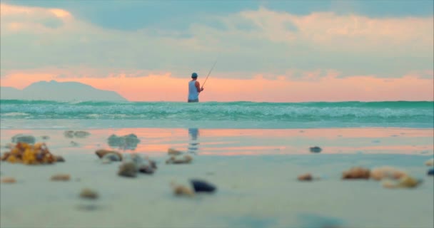 Όμορφο ηλιοβασίλεμα στις τροπικές περιοχές στο φόντο ενός ψαρά που ψαρεύει στο γυρίζοντας στον ωκεανό. Ψαράς που ψαρεύει στη θάλασσα. Έννοια της φύσης, χαλάρωση, χαλαρή. — Αρχείο Βίντεο
