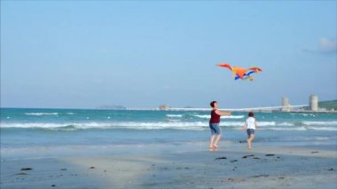 Çocuk uçan uçurtma oynayan mutlu büyükanne, aile büyük uçurtma ile oynarken tropikal bir okyanusun kum üzerinde çalışır. Kavram Mutlu ve kaygısız çocukluk.