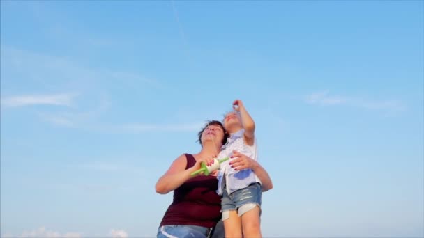 Avó feliz com criança o papagaio voador, a família corre na areia de um oceano tropical brincando com o papagaio mais velho. Conceito Infância feliz e despreocupada . — Vídeo de Stock