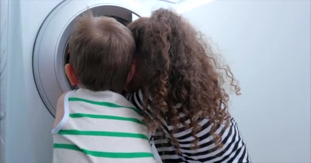 Schattige kinderen zien er in de wasmachine. Cilinder draaiende machine. Concept Wasserij wasmachine, industrie Wasserij service. — Stockvideo