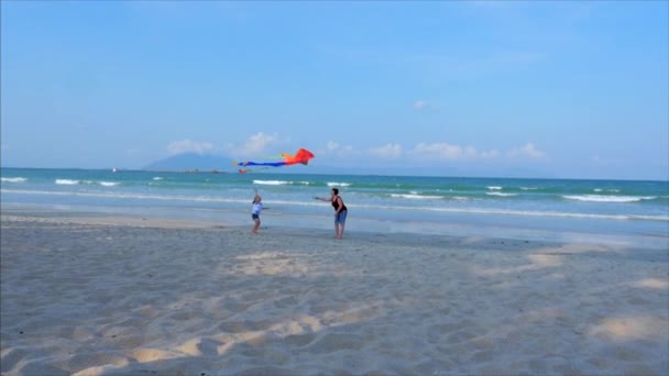 Lycklig mormor med barn att spela flygande kite, familjen körs på sanden i en tropisk Ocean leker med den äldre draken. Concept Happy och bekymmerslös barndom. — Stockvideo