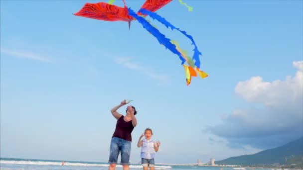 Happy babcia z dzieckiem grając latawiec, Rodzina biegnie na piasku tropikalnego oceanu grając ze starszym latawcem. Koncepcja szczęśliwego i beztrowolego dzieciństwa. — Wideo stockowe