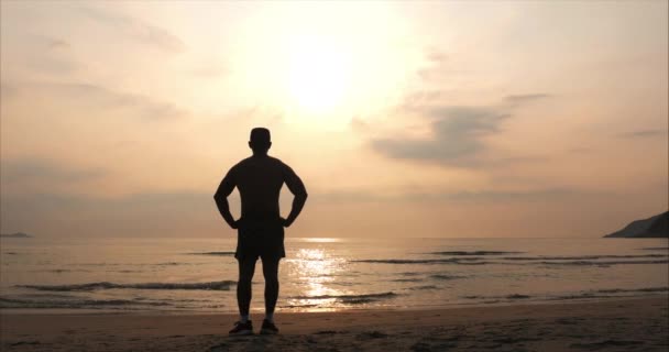 Молодой человек спортсмен глядя на солнце, против заката, тропический фон. Здоровье, спорт, кардио-тренировки . — стоковое видео