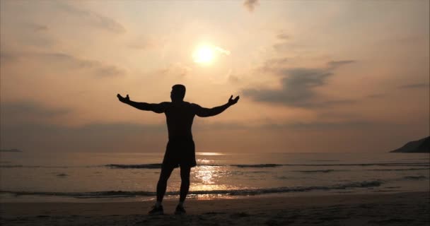 Junger Sportler, der in die Sonne blickt, vor dem tropischen Hintergrund des Sonnenuntergangs. Gesundheit, Sport, Cardio Workout-Konzept. — Stockvideo