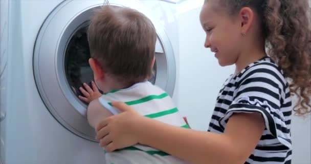 Crianças bonitos olha para dentro da máquina de lavar. Máquina de fiação de cilindro. Conceito Máquina de lavar roupa, Serviço de lavanderia da indústria . — Vídeo de Stock