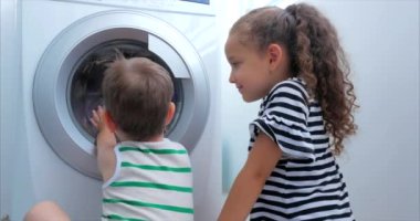 Sevimli Çocuklar Çamaşır Makinesi nin İçine Bakıyor. Silindir İplik Makinesi. Konsept Çamaşır Yıkama Makinesi, Sanayi Çamaşırhane Servisi.