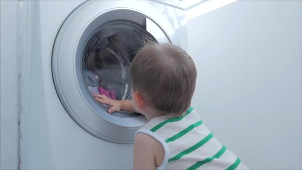 Schattig kind kijkt in de wasmachine. Cilinder draaiende machine. Concept Wasserij wasmachine, industrie Wasserij service. — Stockvideo