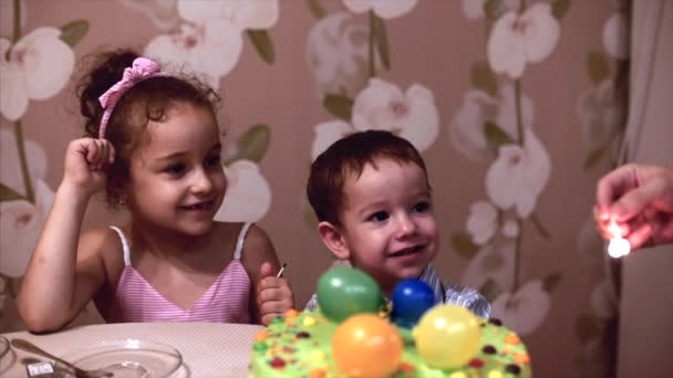 Concetto di famiglia felice. Felice bambino di due anni festeggia il suo compleanno con la sua famiglia, sua madre e la sorellina lo hanno aiutato a spegnere le candele. — Video Stock