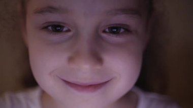 Tablet Pc ile Pight ve resimler bir yansımasıdır gözlerinde ile ilgilenen bir Childs yüz sevimli beyaz küçük kız gece çekim yakın çekim