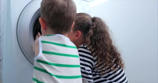 Enfants mignons regarde à l'intérieur de la machine à laver. Machine de rotation de cylindre. Concept Machine à laver la blanchisserie, service de blanchisserie de l'industrie . — Video