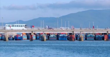 Hareket şehir, otomobil, motosiklet, otobüsler ve birçok kişi ile köprüde trafik, mavi deniz karşı, mavi gökyüzü, yüksek dağlar. Yumuşak odaklama. 4k