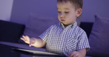 Tablet Ile eğlenceli sevimli çocuk. Küçük çocuk harcama boş zaman oynamak mobil oyun ve El Ile parlak ekran Hahes. Konsept: mutlu Childfood, teknoloji, Childen oyun oyunları