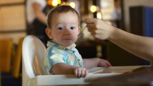 Μητέρα δίνει παιδικές τροφές από το κουτάλι το μωρό σε ένα εστιατόριο, ένα παιδί τρώει πρόθυμα. 4k. — Αρχείο Βίντεο