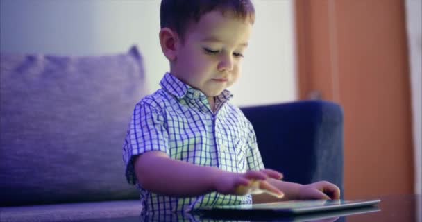 Criança bonito entretendo com Tablet. Little Boy gasta tempo de lazer jogando jogo móvel no e esmaga a tela brilhante com sua mão. Conceito de: Happy Childfood, Tecnologia, Jogos infantis — Vídeo de Stock