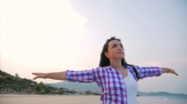 Woman with arms raised On a Tropical Beach Close-Up Portrait of European Beautiful Cute Brunette, Young Woman or Cheerful Girl lifting Arms Up Celebrating Life Scenic Landscape, Blowing Wind Hair the