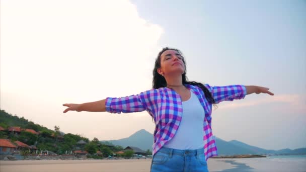 Mujer con los brazos levantados En una playa tropical Primer plano Retrato de Europea Hermosa Linda Morena, Mujer Joven o Chica Alegre levantando los brazos Celebrando la vida Paisaje escénico, Soplando el viento Pelo — Vídeo de stock