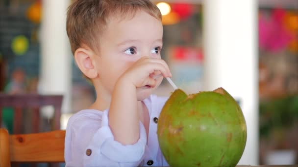 Roztomilé dítě pije kokosový koryto a sláma, zblízka. . Koncept: děti, šťastné dětství, léto, Baby, dovolená. — Stock video