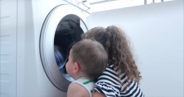 Sevimli Çocuklar Çamaşır Makinesi nin İçine Bakıyor. Silindir İplik Makinesi. Konsept Çamaşır Yıkama Makinesi, Sanayi Çamaşırhane Servisi.