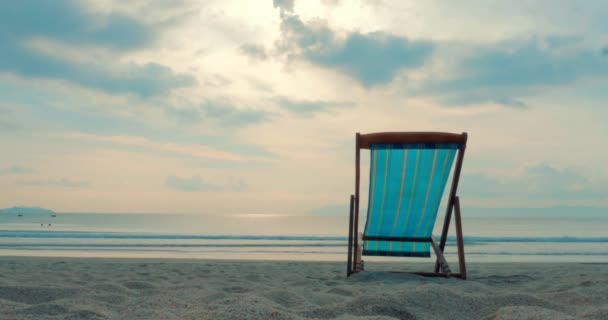 Zblízka na tropické pláži Chaise Longue na písku, na pozadí moře a nádherný západ slunce nebo východ slunce, podél tropického pobřeží, proti oceánu. — Stock video