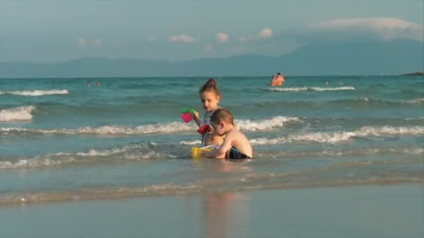 Enfants heureux et insouciants jouant au bord de la mer avec du sable. Enfants jouant, frère et sœur jouant au bord de la mer. Bonne enfance . — Video