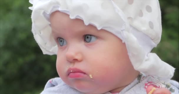 Close-Up al rallentatore girato di cinque mesi Baby Girl seduta all'aperto in un passeggino a guardare la fotocamera. Guarda il bambino nella telecamera da vicino. Concetto di Infanzia, bambino, bambini . — Video Stock